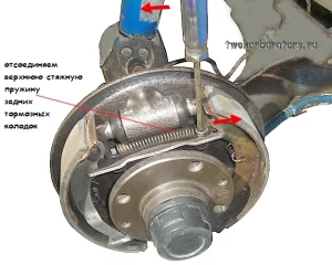 Отверткой снимаем верхнюю стяжную пружину задних тормозных колодок